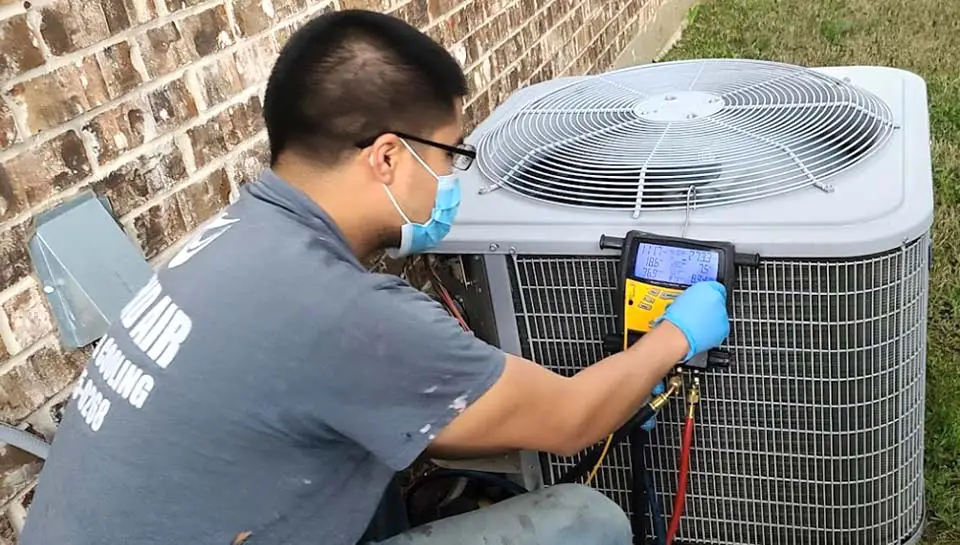 A qualified technician from Legend Air performs a maintenance check on a customer's air conditioner